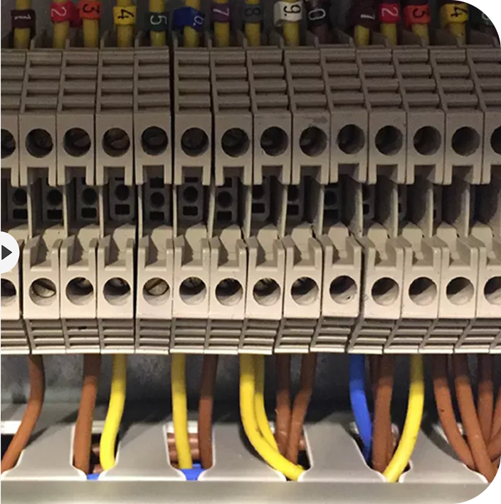 Close-up of an electrical terminal block with multiple color-coded wires connected to numbered slots.