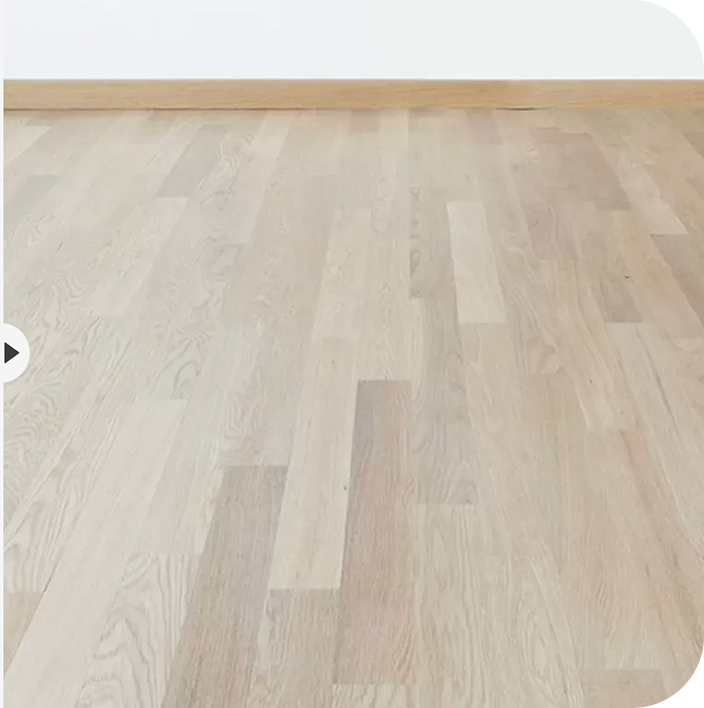 Light wood parquet flooring with a wooden baseboard against a plain white wall.