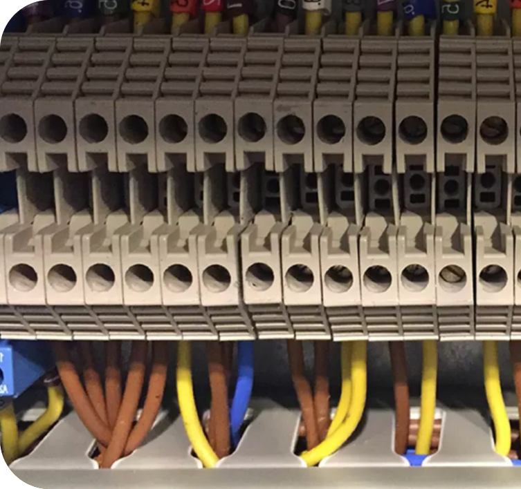Close-up of multiple electrical terminal blocks with yellow, brown, and blue wires connected underneath.