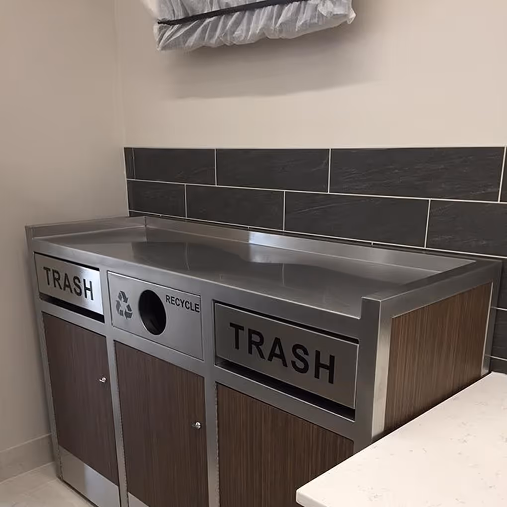 Stainless steel trash and recycling bin with two trash compartments and one recycling compartment.