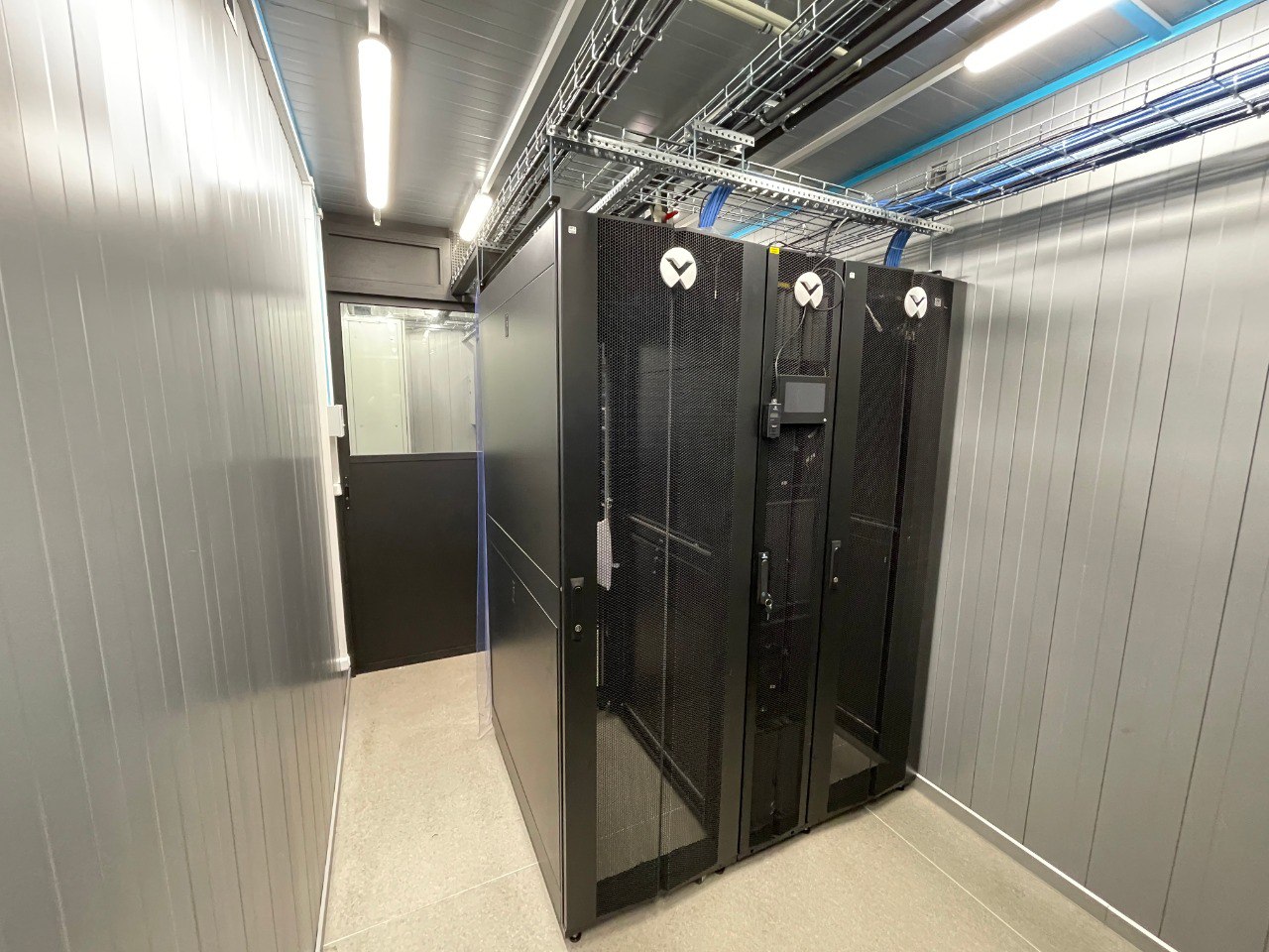 Interior of mobile modular data center with Vertiv server racks, overhead cable management trays, fire suppression system, and structured cabling