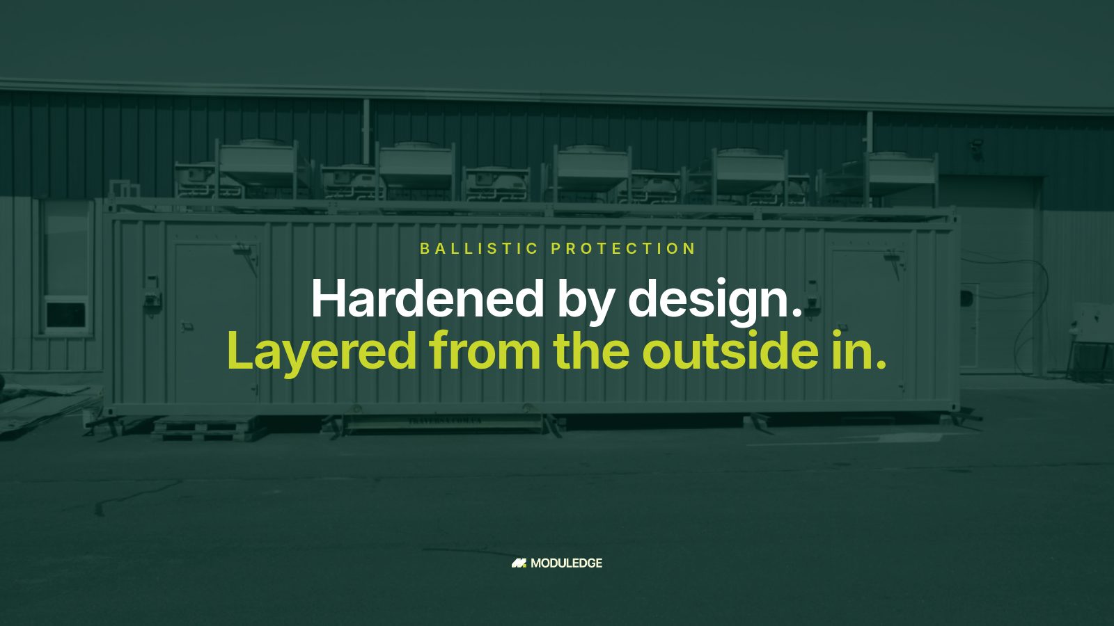 Long side of a white modular data-center container beside an industrial building, with the headline "Hardened by design. Layered from the outside in."