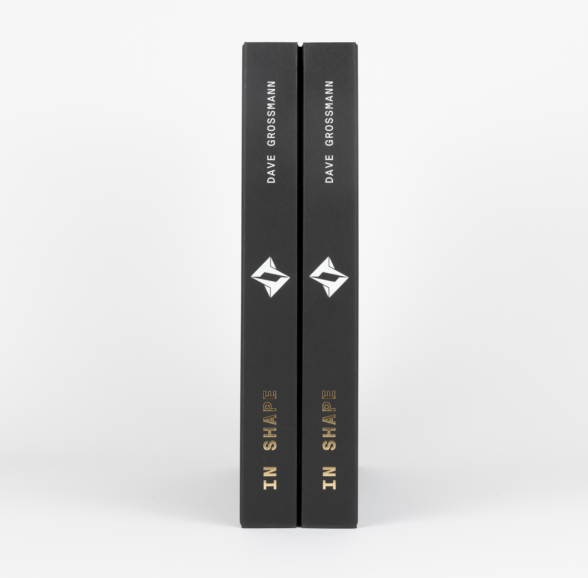 Two identical black books standing upright, titled 'IN SHAPE' by Dave Grossmann with a white geometric logo.