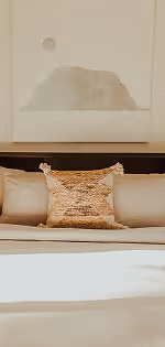 Beige sofa with a textured decorative pillow and abstract wall art of a sun over a hill.