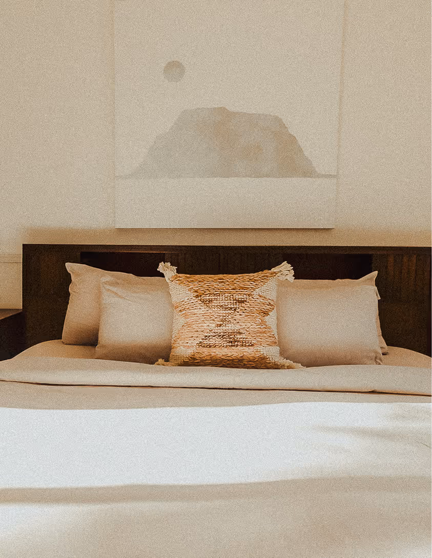 A bed with pillows and a painting above it.