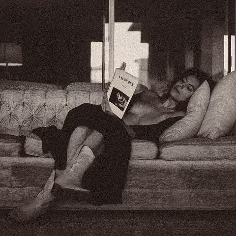 A man laying on a couch reading a book.