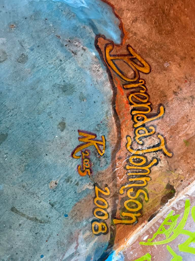 Colorful graffiti on a rough surface with the name 'Brenda Johnson' and the years '2005' and '2008' painted in orange and yellow tones.