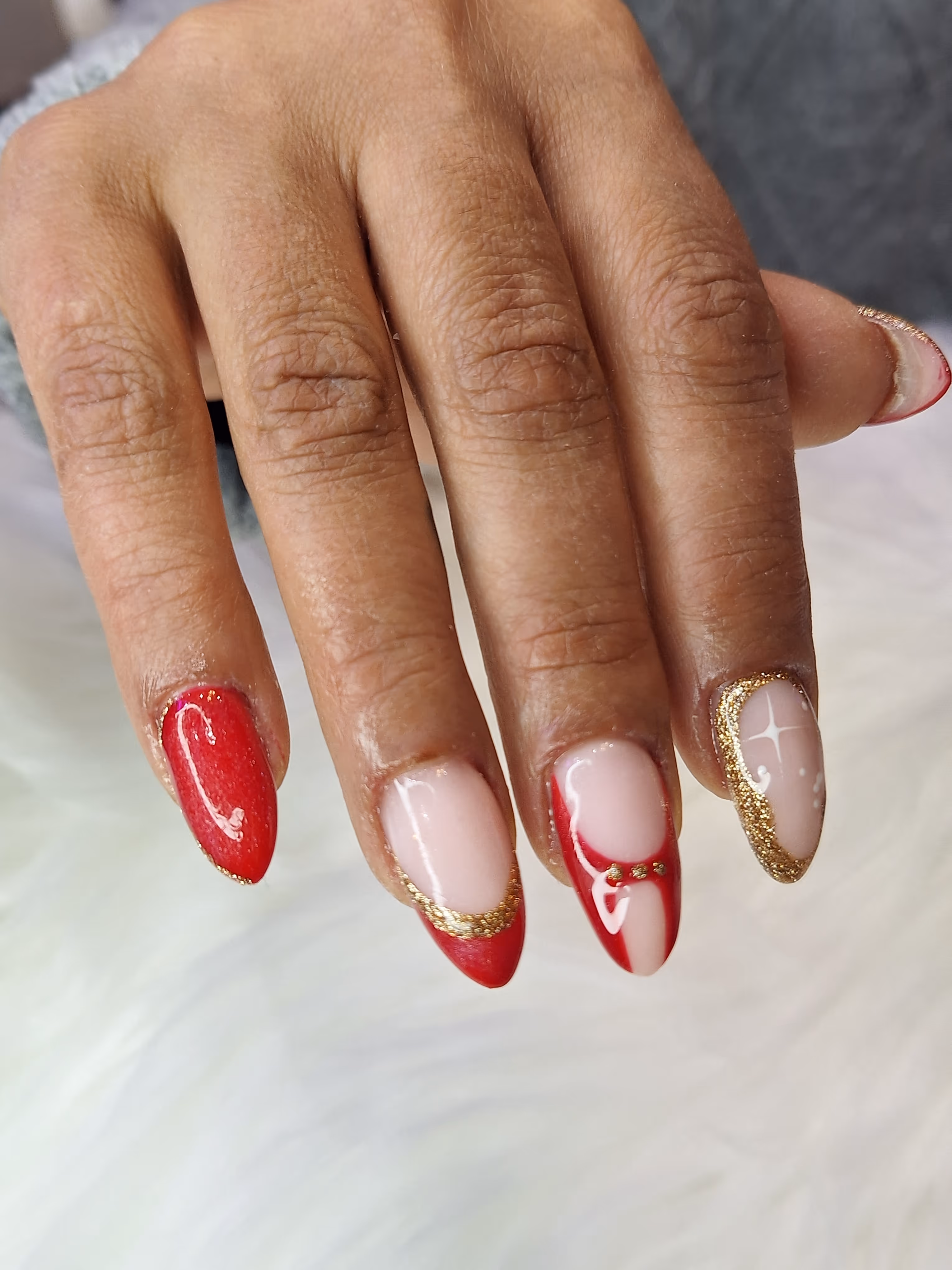 Eine Hand mit weiß-rotem Nageldesign – Maniküre