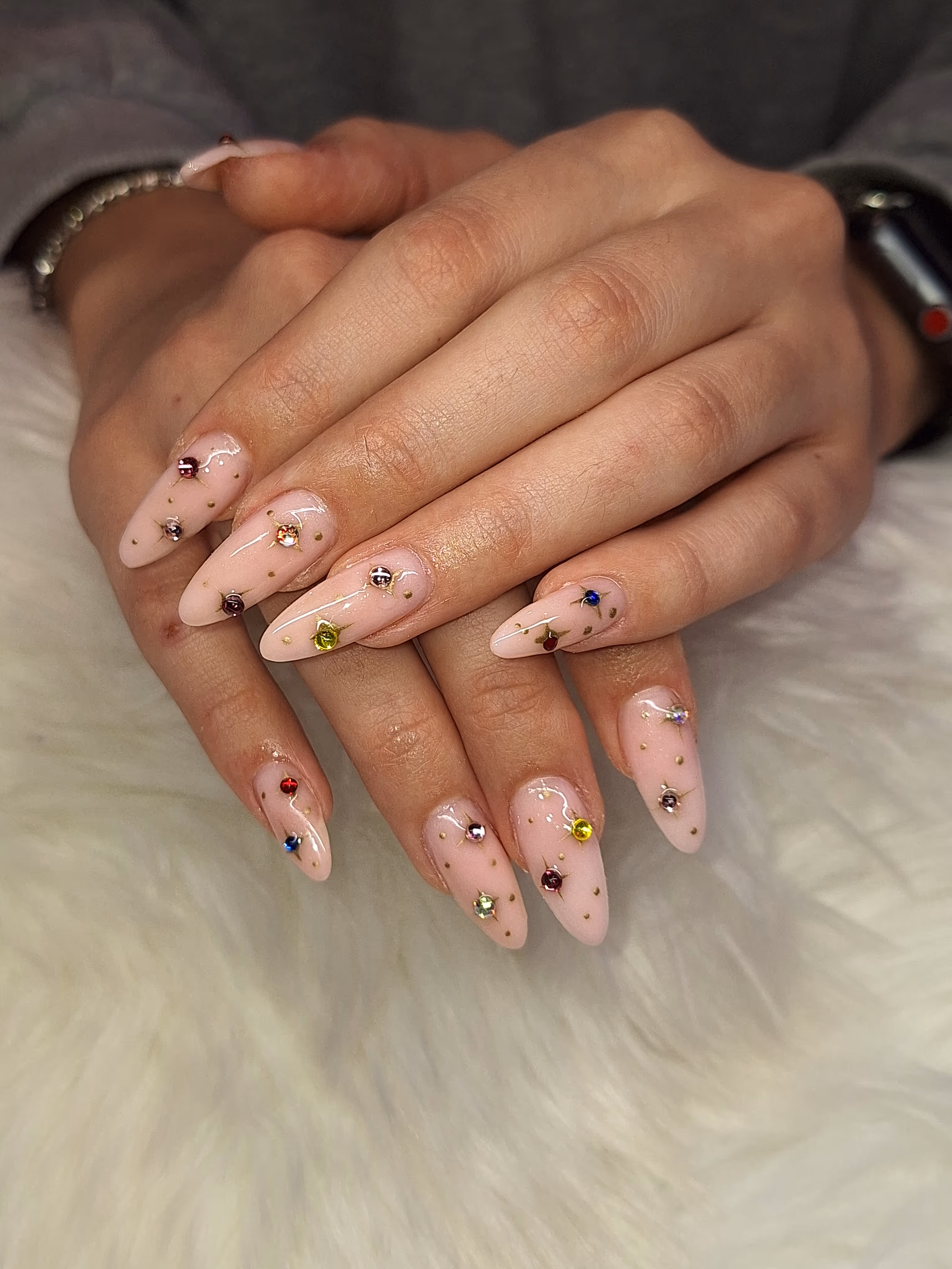 Zwei Hände mit pinkem Nageldesign und kleinen Steinchen – Maniküre