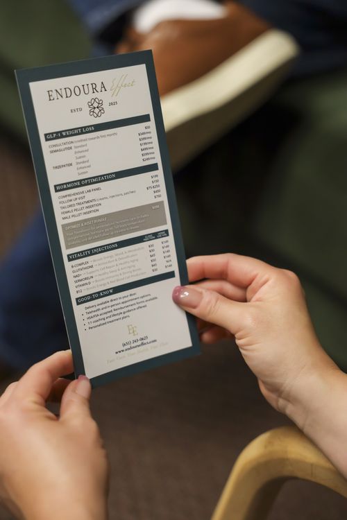 Person holding a brochure detailing Endoura Effect's weight loss, hormone optimization, and vitality injection services with prices.