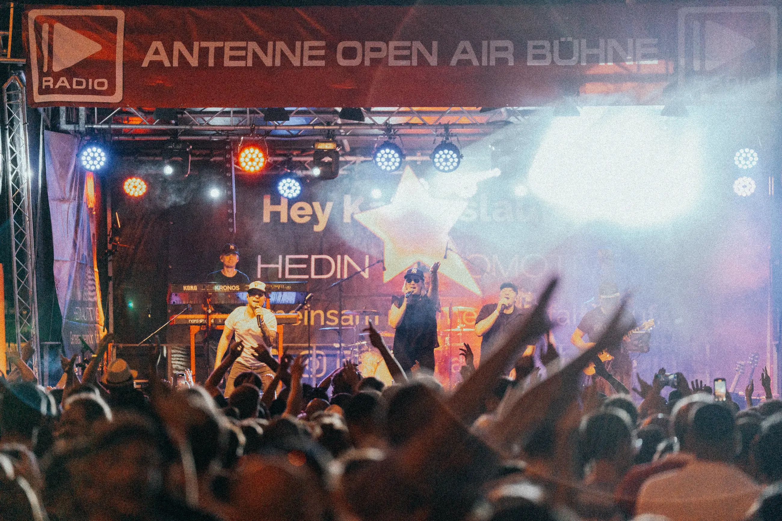 Live-Konzert mit einer Band auf der ANTENNE Open Air Bühne vor einem jubelnden Publikum bei Nacht.