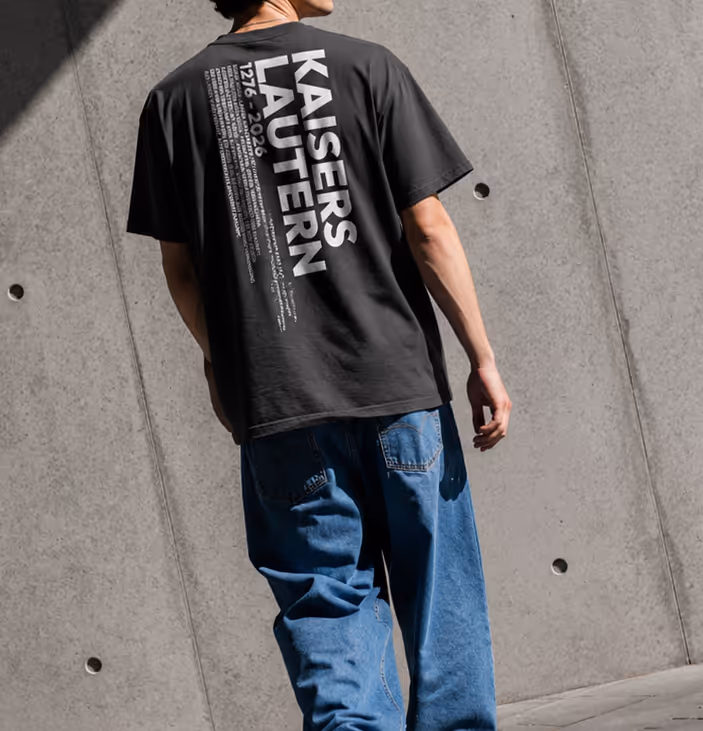 Eine Person trägt ein schwarzes T-Shirt mit der großen Aufschrift Kaiserslautern und Jahreszahlen 1276-2026.