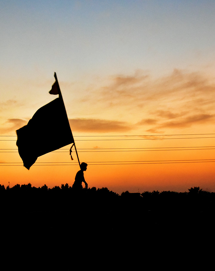 Better Flags | CiClO Flags | Silhouette of a person holding a large flag against a sunset sky with orange and blue hues.