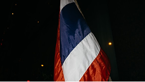 Better Flags | CiClO Flags | Close-up of a vertically hanging flag with blue, white, and red stripes in low light.