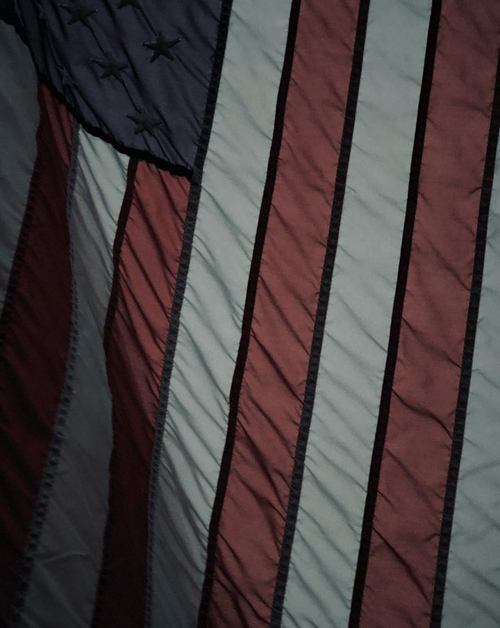 Better Flags | CiClO Flags | Close-up of a wrinkled American flag showing red and white stripes and a blue section with stitched black stars.