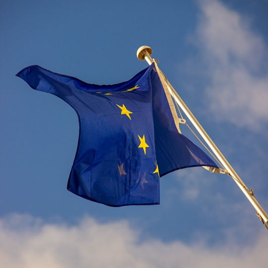 Better Flags | CiClO Flags | Blue flag with gold stars waving against a partly cloudy sky.