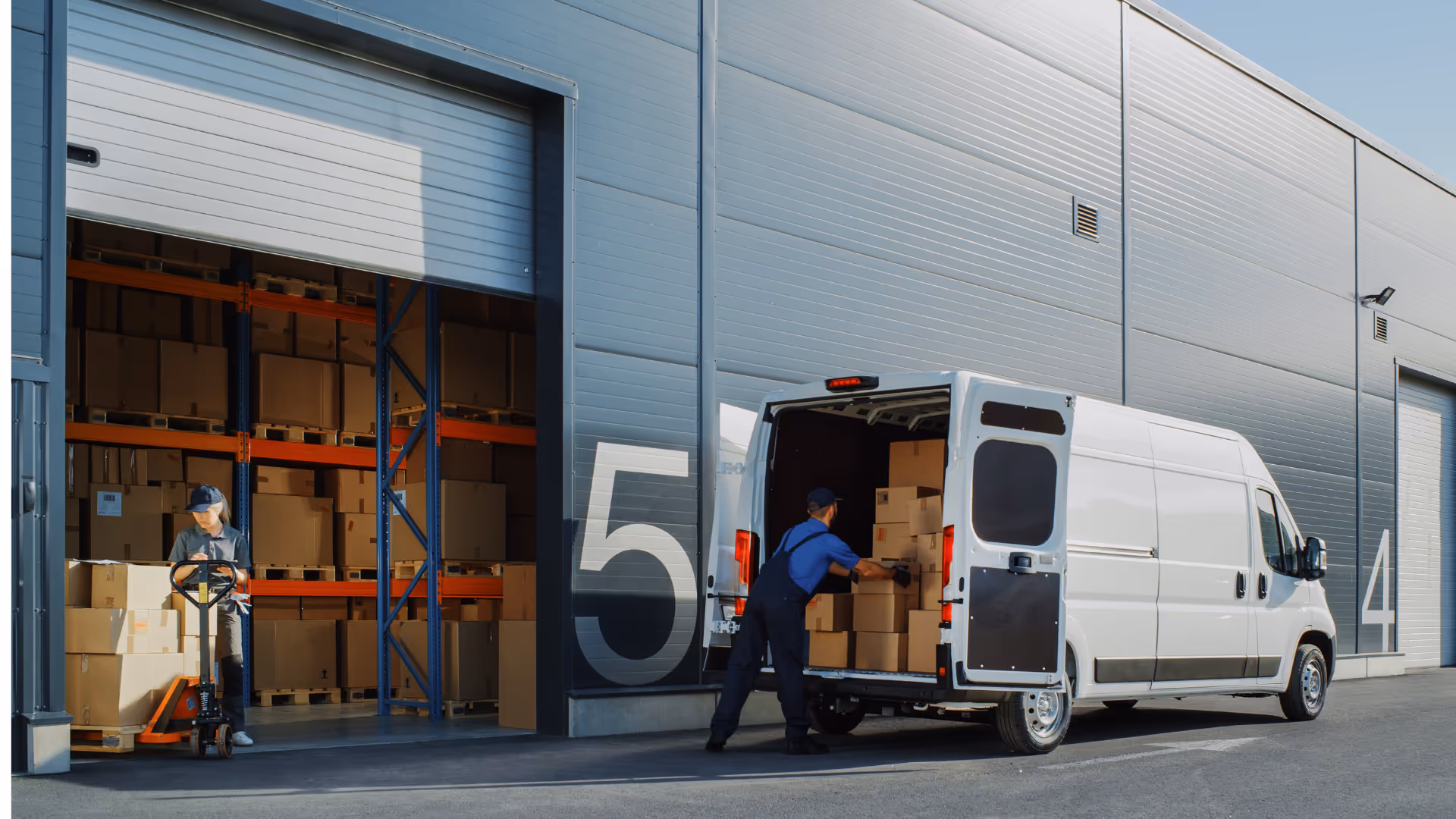 Warehouse worker unloading cardboard boxes from a white delivery van near a loading dock.