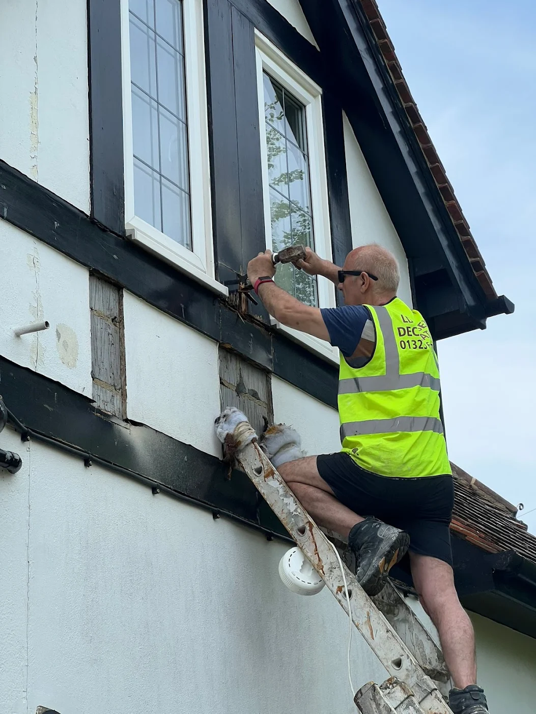 Levent Demiralp, the founder, repairing wooden beams on the front of a heritage property in Eastbourne, East Sussex.