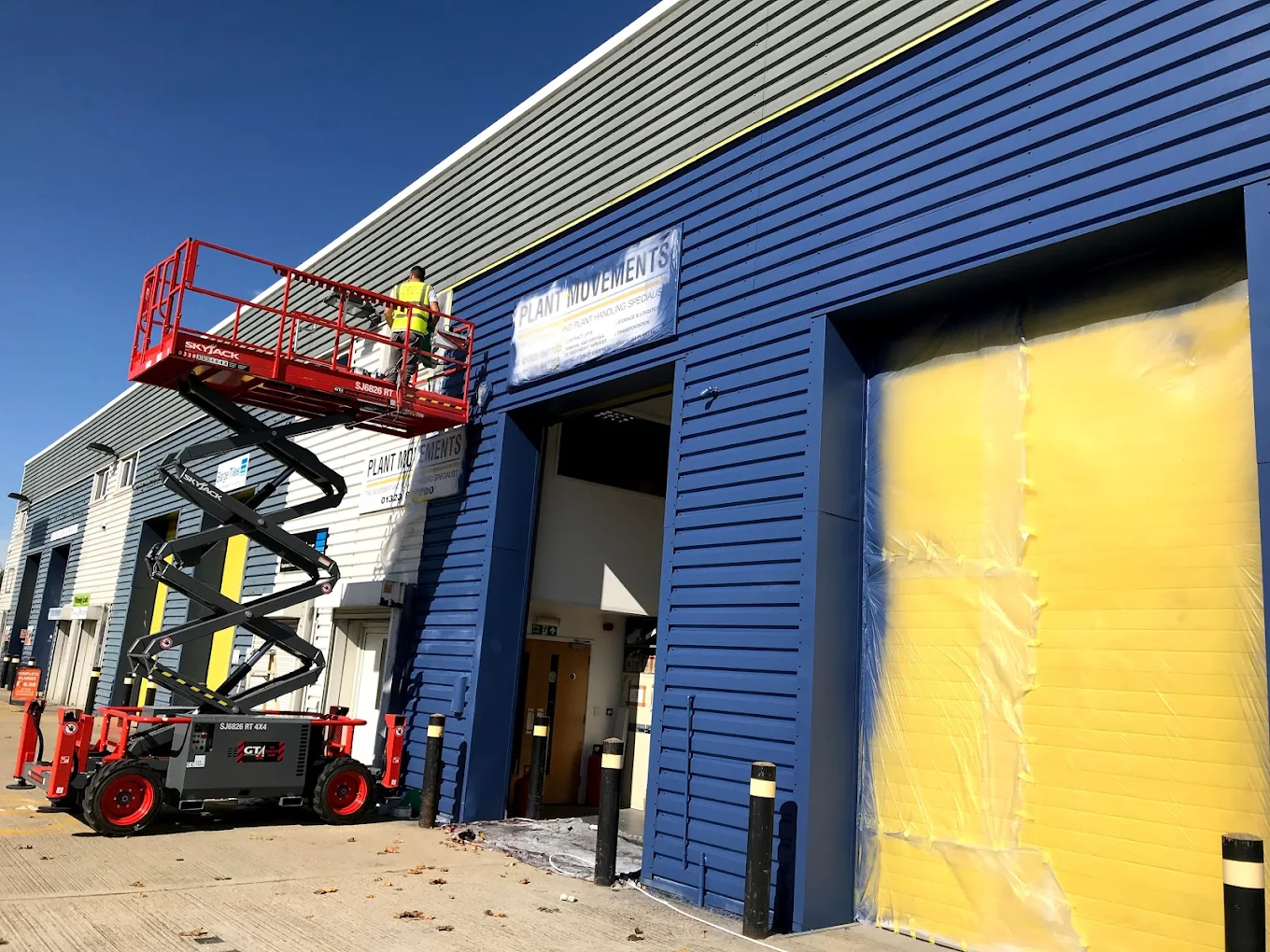 A scissor lift being used to spray paint the exterior of the Topline industrial premises near Hailsham