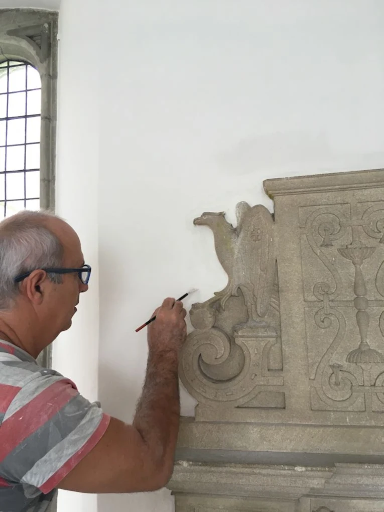 Founder, Levent Demiralp, carefully painting around a grand fireplace at Herstmonceux Castle