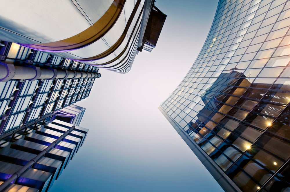 Upward view of modern skyscrapers with glass facades against a clear sky.