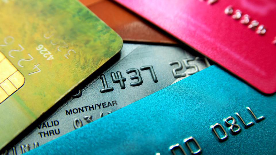 Close-up of overlapping colorful credit cards showing embossed numbers and expiration dates.