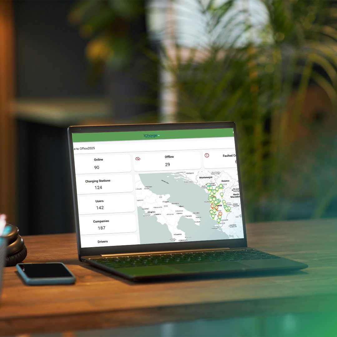 Laptop on wooden table displaying a dashboard with charging station statistics and a map of the Balkans region.