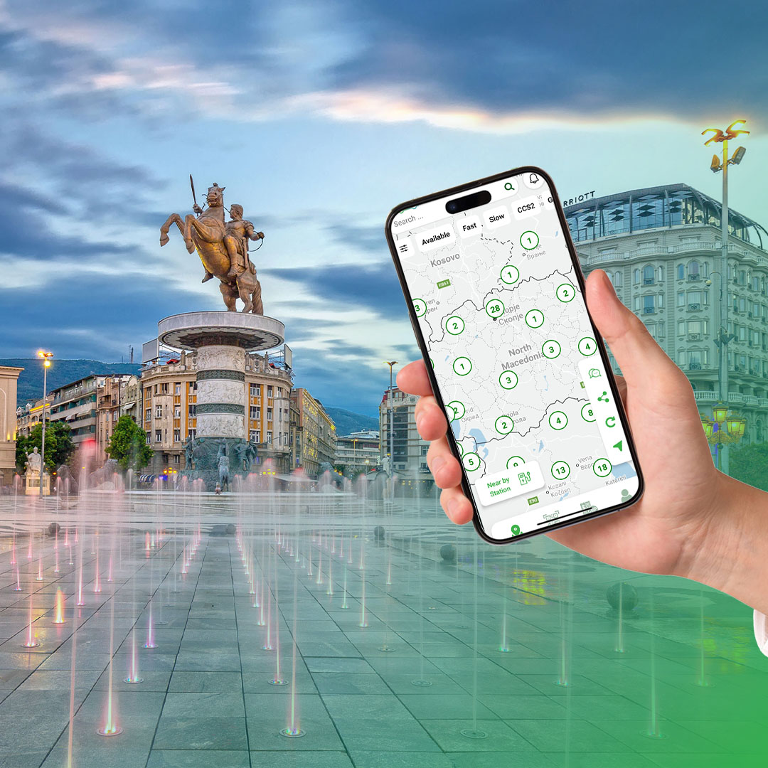 Hand holding smartphone displaying a map of North Macedonia with location markers, in front of the Warrior on a Horse statue and fountains in Skopje city square.