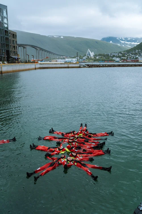 Group of people wearing red survival suits floating in freezing water -  Authentic North