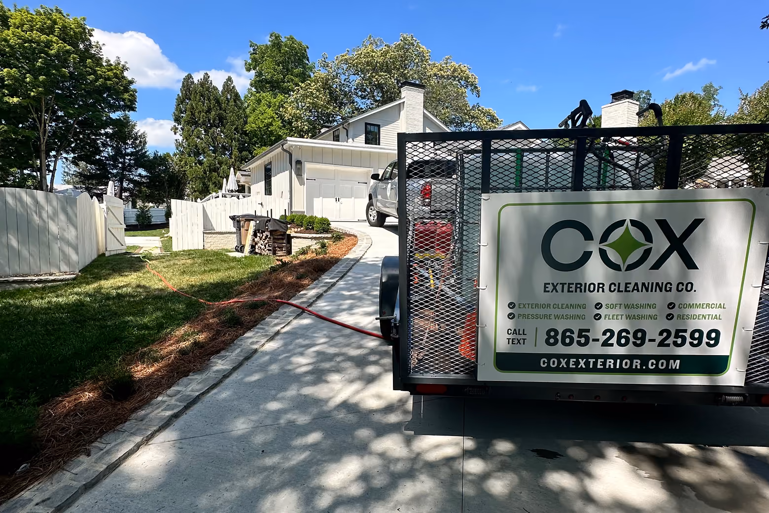 Cox Exterior Cleaning Co. pressure washing trailer parked at a house.