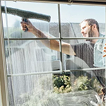 A photo of a man cleaning a window
