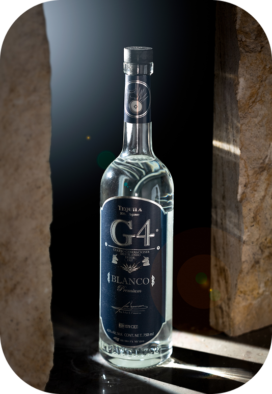 Bottle of G4 Blanco premium tequila with black label, placed between two stone pillars in low light.