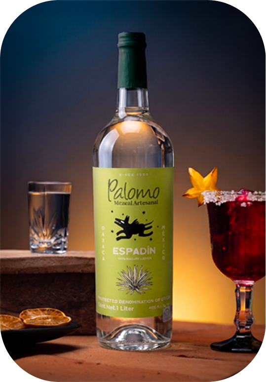 Palomo Mezcal Artesanal Espadin bottle with glass of mezcal and red cocktail with starfruit garnish.