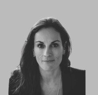 Black and white headshot of a woman with long dark hair wearing a dark blazer against a plain background.