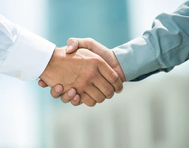 Close-up of two people shaking hands indoors, symbolizing agreement or partnership.