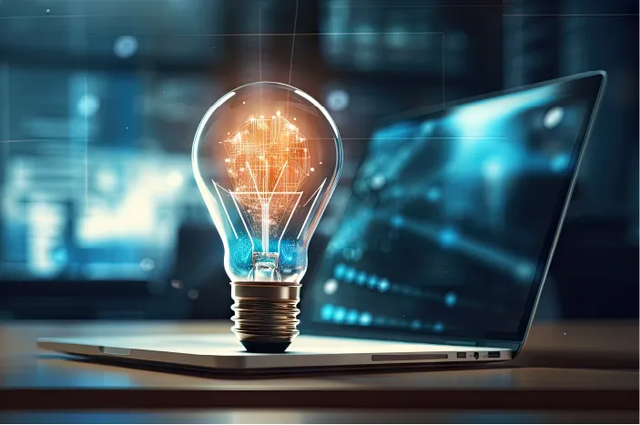 Light bulb with glowing digital circuitry inside placed on a laptop keyboard symbolizing innovation and technology.