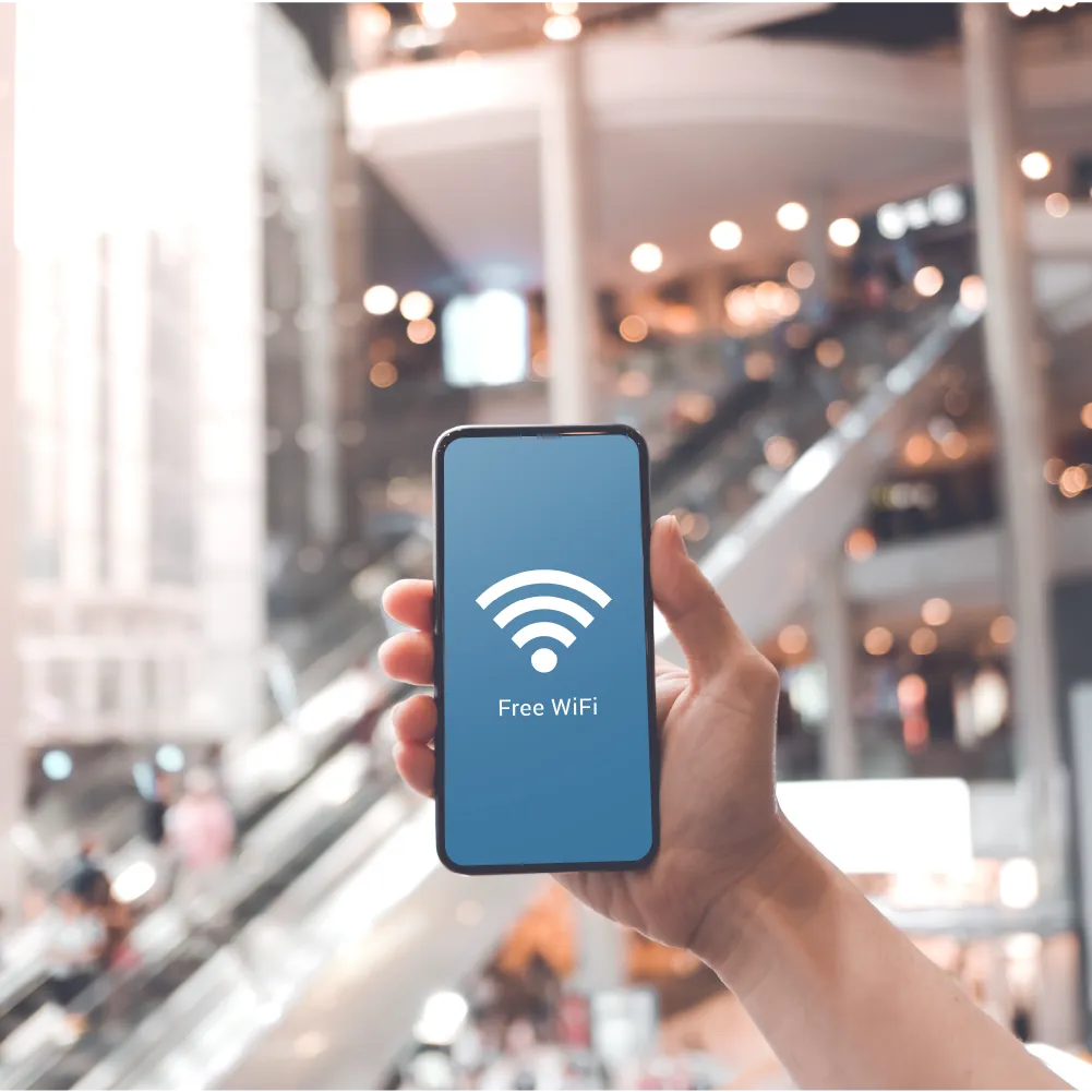Hand holding smartphone with screen displaying free WiFi symbol in a shopping mall.