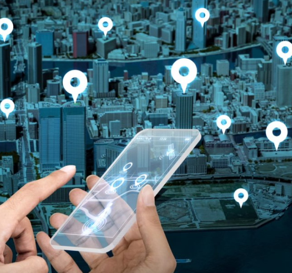 A person holding a transparent smartphone with digital location pins over a cityscape in the background, representing smart city navigation technology.