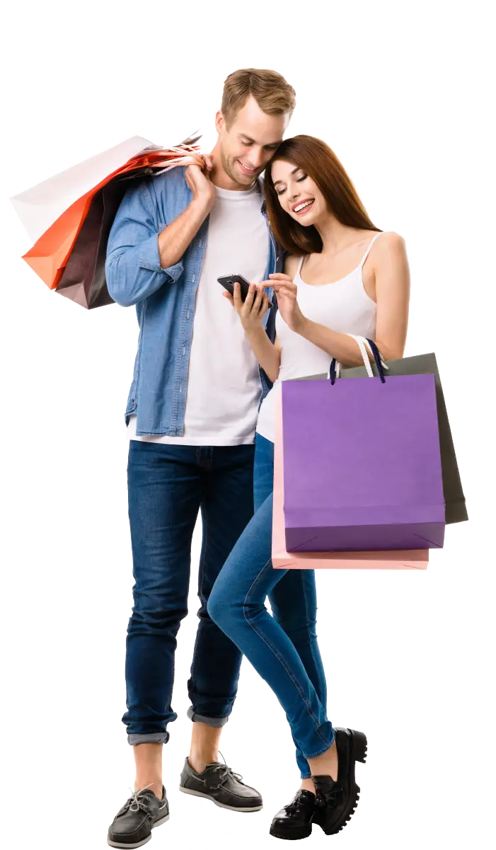 Smiling young couple holding shopping bags and looking at a smartphone together.