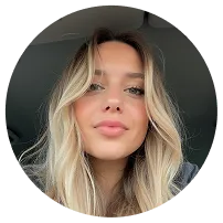 Junge Frau mit langen blonden Haaren und natürlichem Make-up, die in die Kamera lächelt.