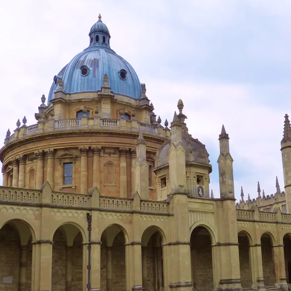 Historic building with a large blue dome and intricate stone arches under an overcast sky.