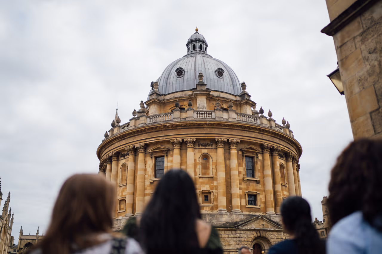 Four people looking at the Radcliffe Camera, a circular historic building with a domed roof.