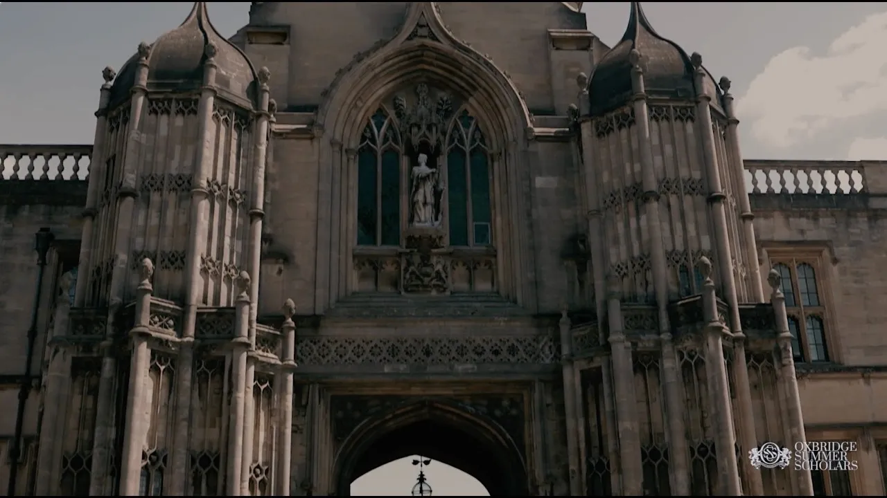 Ornate stone archway with statues and gothic windows at a historic university building.