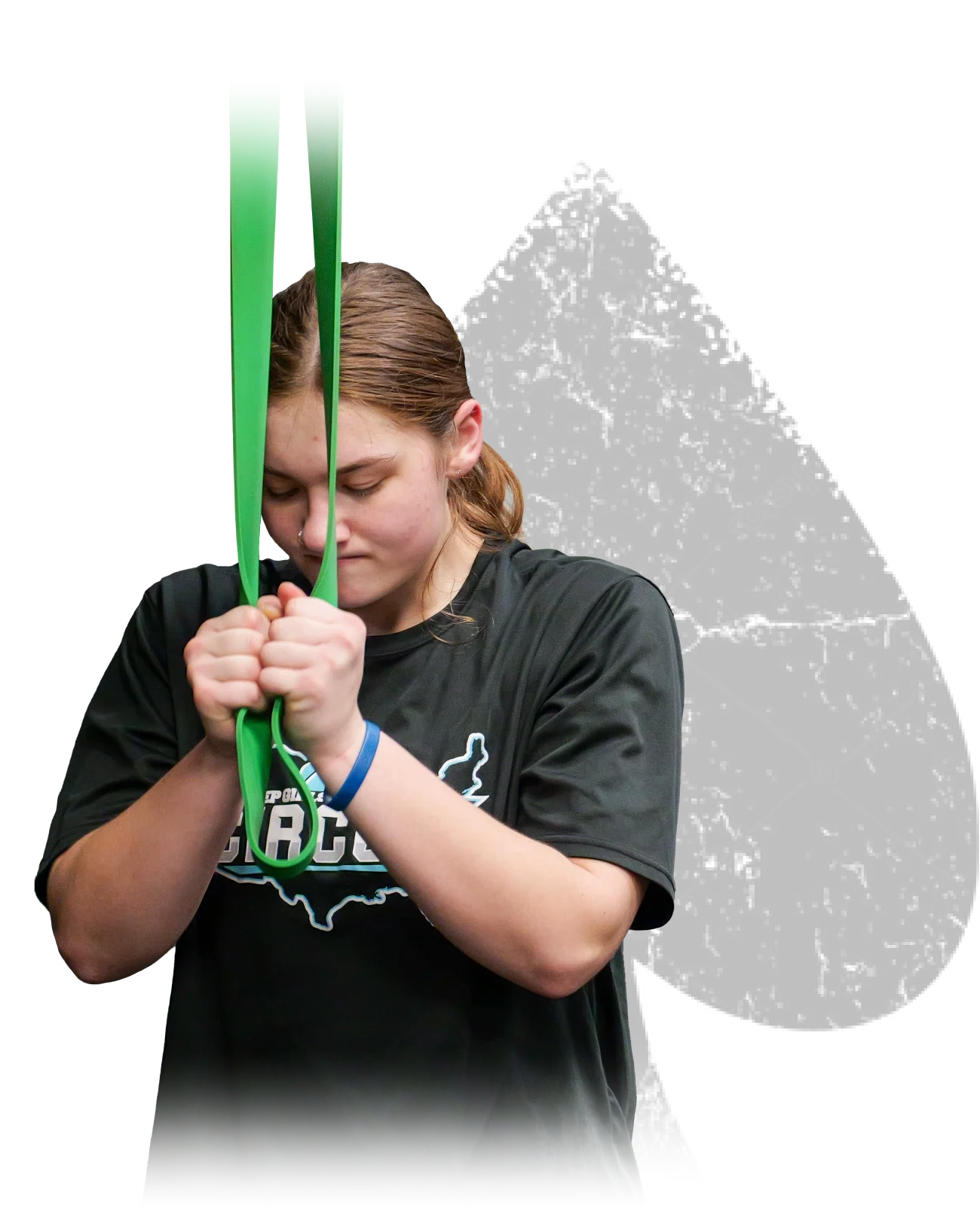 Young woman in a black t-shirt using a green resistance band for exercise with her hands clenched and arms bent.