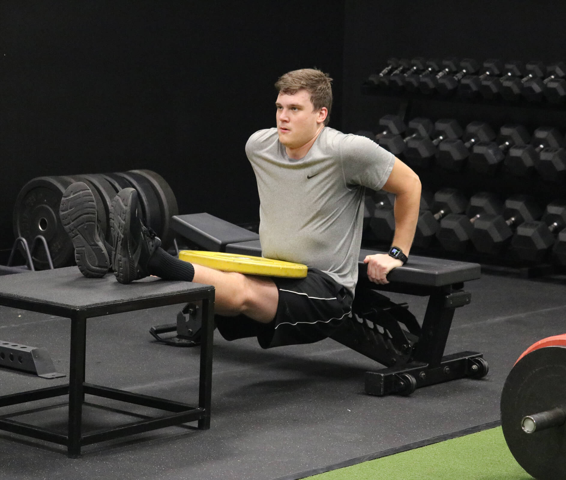 Athlete performing leg exercise with weight plate in gym