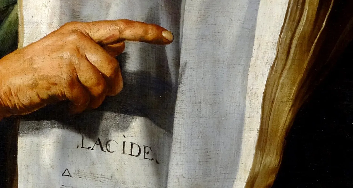 Close-up of a hand with an extended index finger pointing, resting on white fabric with partially visible text.
