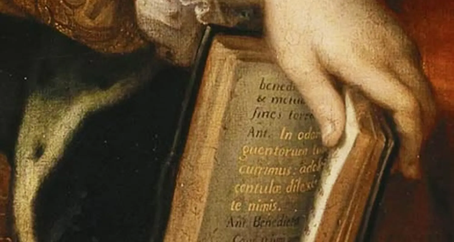 Close-up of a hand turning a page of an old book with Latin text.