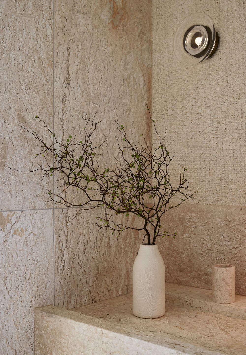 Omaha Retreat bathroom detail with layered natural stone, textured wall finish and sculptural lighting, designed by Sonya Cotter.