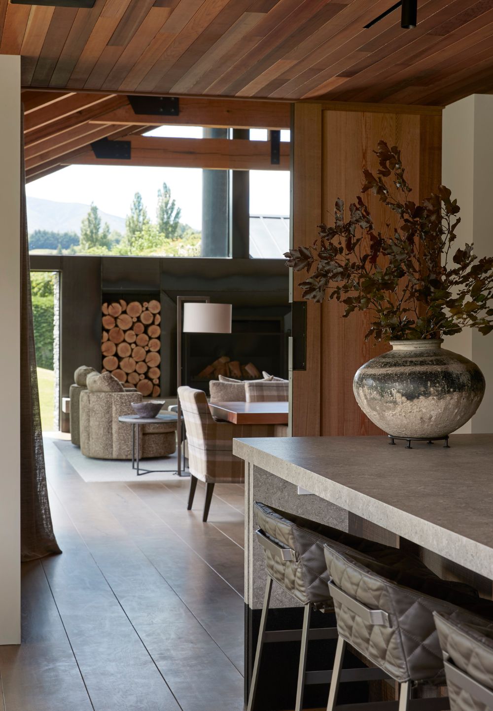 Speargrass Home Queenstown kitchen with timber-lined ceiling, stone island and views through to the dining area