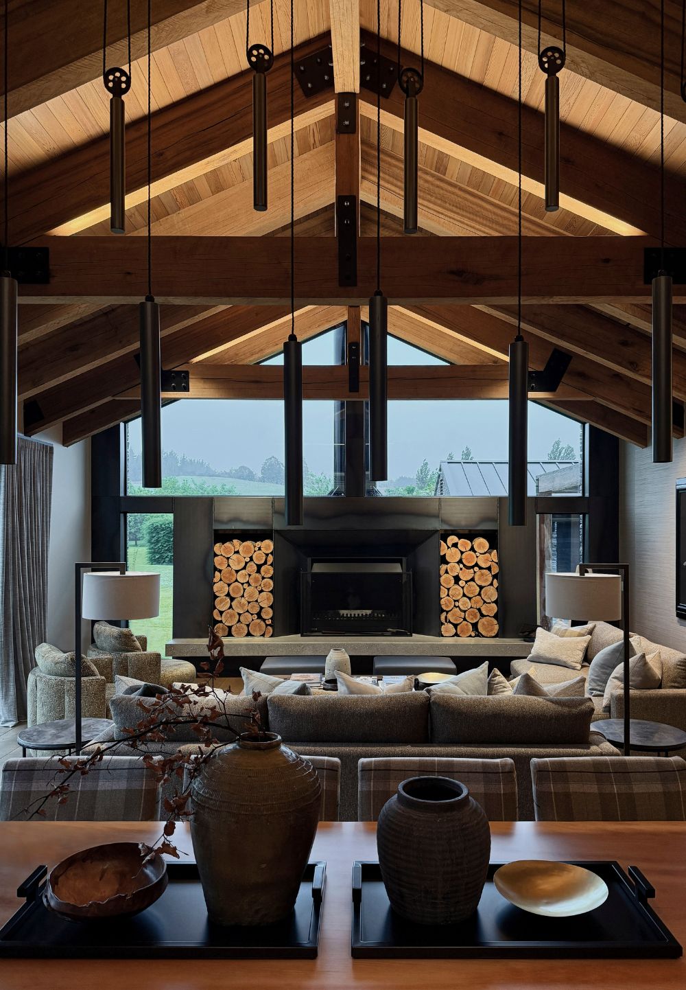 Speargrass Home Queenstown living room with vaulted timber ceiling, stone fireplace and layered furnishings